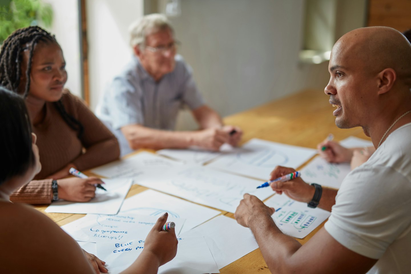 Diverse professionals brainstorm ideas at a wooden table.
